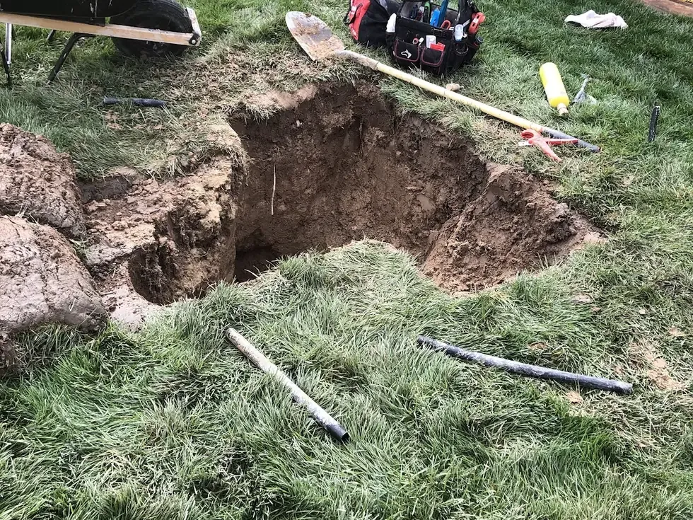 Hand-dug access pit exposing a service line in a Nampa lawn